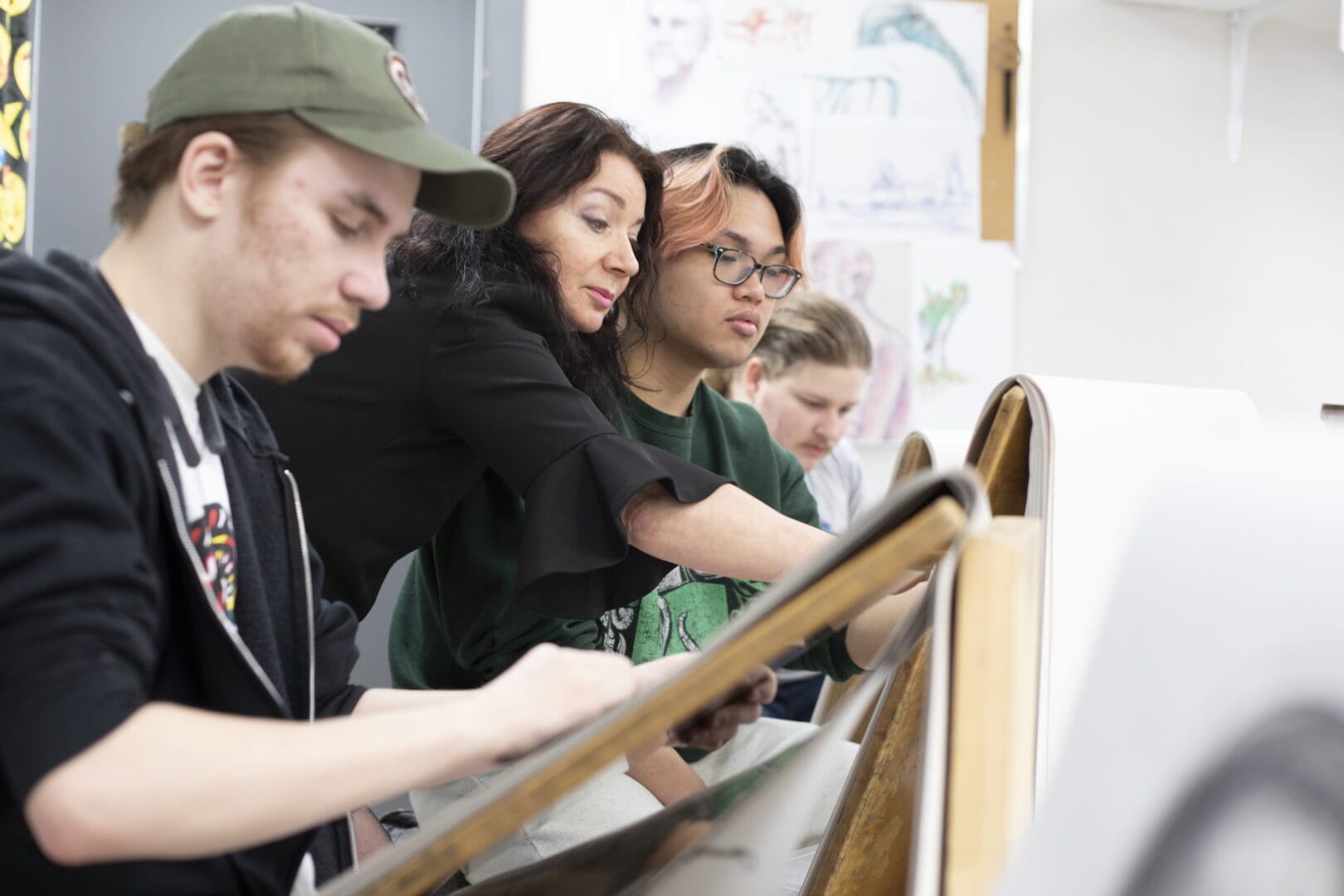 An Instructor at College for Arts and Technology guides a student through a life drawing exercise using an easel in a drawing classroom.